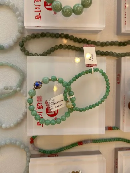 A product photo of green bead bracelets on a display stand